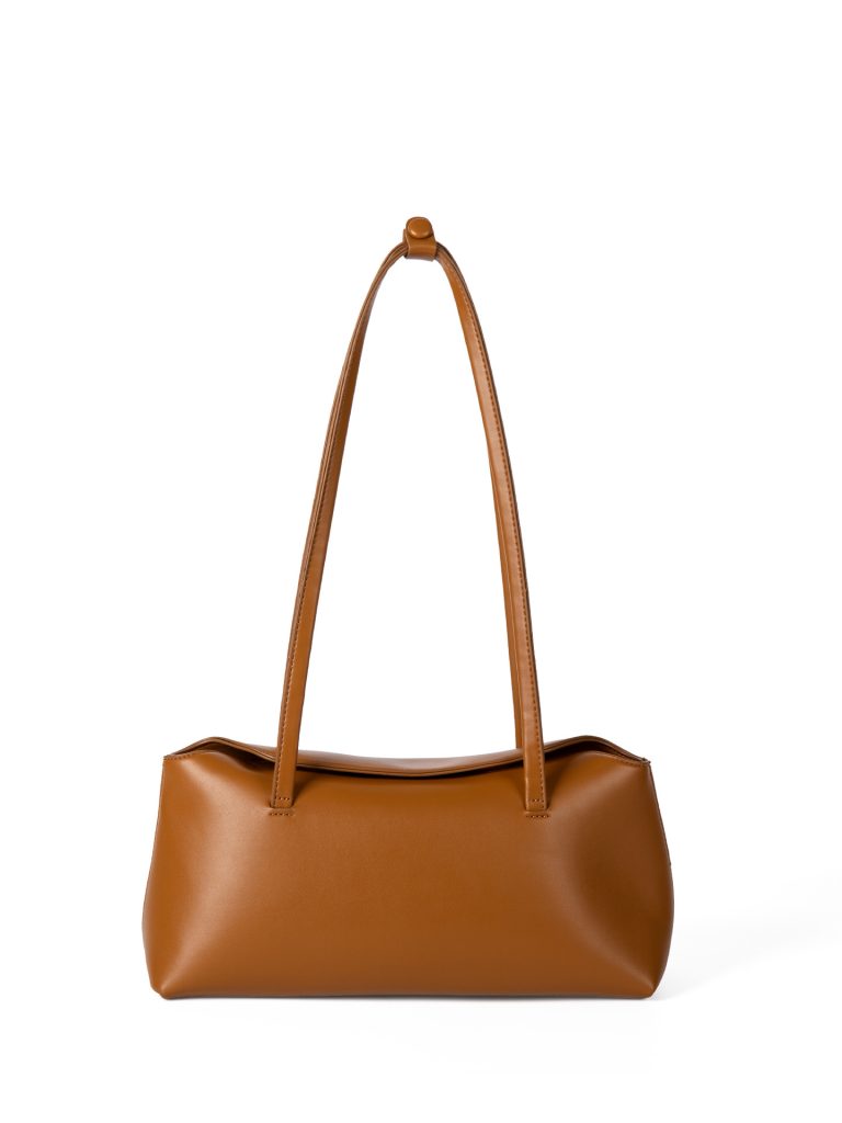 A cognac brown vegan leather baguette shoulder bag with long slim straps and a softly curved top, shown on a white background.