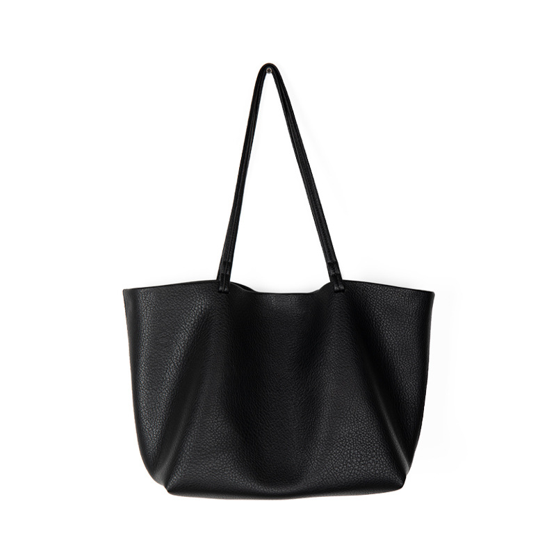 A slouchy black pebbled vegan leather tote with long thin shoulder straps and an open trapezoid silhouette.