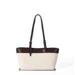 An off-white canvas tote with black vegan leather top trim, base, and adjustable shoulder straps. Additional product view 3.