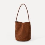 A small black faux suede bucket bag with a thin tubular strap and a silver chain charm at the strap base. Additional product view 6.
