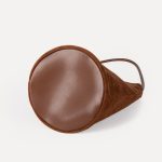 A small black faux suede bucket bag with a thin tubular strap and a silver chain charm at the strap base. Additional product view 7.