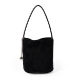 A small black faux suede bucket bag with a thin tubular strap and a silver chain charm at the strap base.