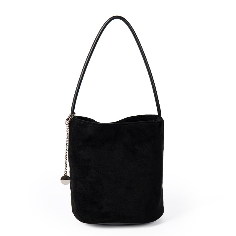 A small black faux suede bucket bag with a thin tubular strap and a silver chain charm at the strap base.