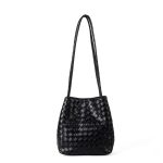 A black woven vegan leather bucket shoulder bag with matching tubular straps and a tight diagonal intrecciato weave.