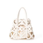 A black laser-cut vegan leather cage tote with a cream drawstring inner pouch and two matching top handles. Additional product view 4.
