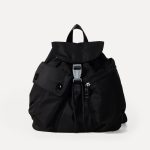 A small black nylon backpack with a drawstring flap, translucent buckle, angled front pocket, and webbing shoulder straps. Additional product view 5.
