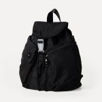 A small black nylon backpack with a drawstring flap, translucent buckle, angled front pocket, and webbing shoulder straps. Additional product view 6.