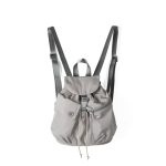 A small black nylon backpack with a drawstring flap, translucent buckle, angled front pocket, and webbing shoulder straps. Additional product view 4.