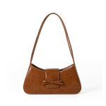A cognac brown vegan leather baguette shoulder bag with a small front bow on the flap and a slim underarm strap.