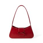 A cognac brown vegan leather baguette shoulder bag with a small front bow on the flap and a slim underarm strap. Additional product view 4.