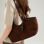 A black faux suede tote with a scooped top, smooth vegan leather trim, and adjustable buckled shoulder straps. Additional product view 4.
