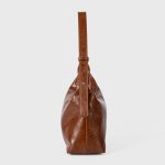 A glossy black crinkled vegan leather crescent underarm bag with a knotted side strap and a silver zipper pull. Additional product view 6.
