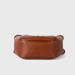 A small black vegan leather bucket bag with dual top handles and a gold-tone buckle strap wrapped around the body. Additional product view 8.