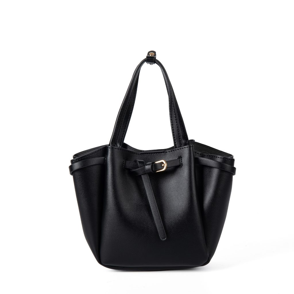 A small black vegan leather bucket bag with dual top handles and a gold-tone buckle strap wrapped around the body.