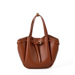 A small black vegan leather bucket bag with dual top handles and a gold-tone buckle strap wrapped around the body. Additional product view 3.