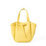 A small black vegan leather bucket bag with dual top handles and a gold-tone buckle strap wrapped around the body. Additional product view 6.