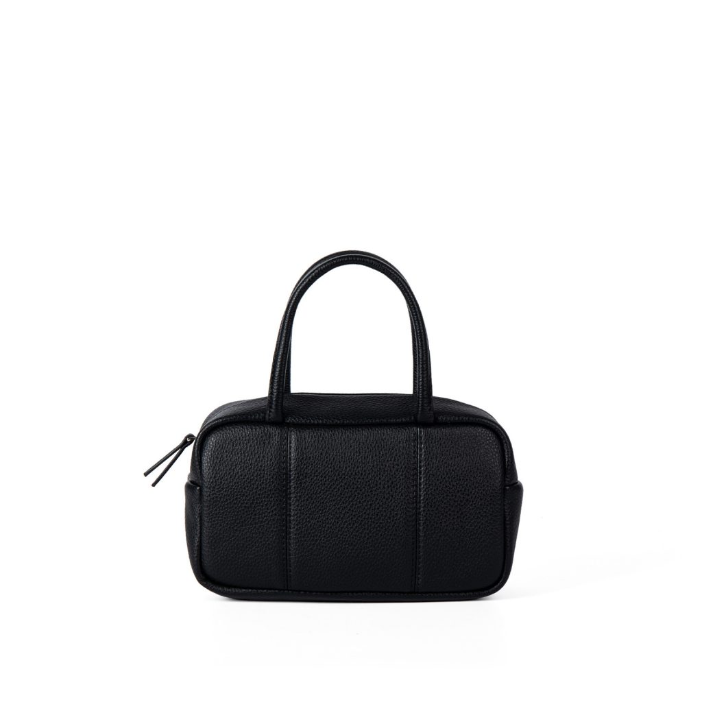 A boxy black pebbled vegan leather mini Boston bag with rolled top handles and long zipper pulls.