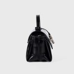 A glossy black structured vegan leather handbag with a thin top handle and a silver cross-bar toggle clasp. Additional product view 6.