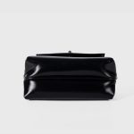 A glossy black structured vegan leather handbag with a thin top handle and a silver cross-bar toggle clasp. Additional product view 8.
