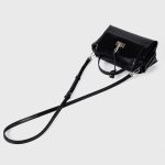 A glossy black structured vegan leather handbag with a thin top handle and a silver cross-bar toggle clasp. Additional product view 9.