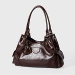 A shiny black vegan leather hobo shoulder bag with a row of silver studs, side flap pockets, and a hanging heart charm. Additional product view 5.