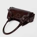 A shiny black vegan leather hobo shoulder bag with a row of silver studs, side flap pockets, and a hanging heart charm. Additional product view 8.