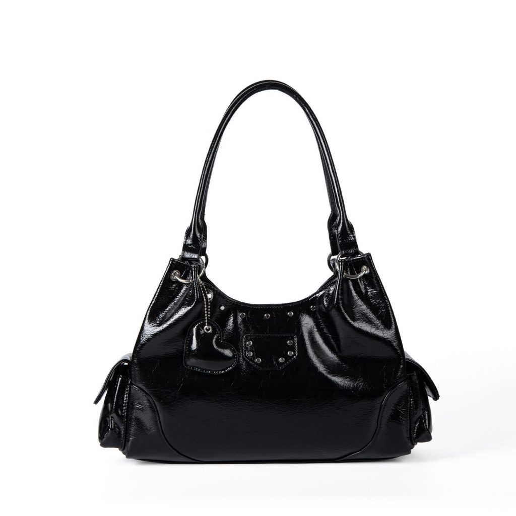 A shiny black vegan leather hobo shoulder bag with a row of silver studs, side flap pockets, and a hanging heart charm.
