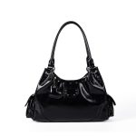 A shiny black vegan leather hobo shoulder bag with a row of silver studs, side flap pockets, and a hanging heart charm.