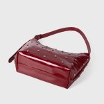 A glossy black vegan leather crescent bag covered in small silver studs, with an adjustable strap and top zipper. Additional product view 6.