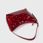 A glossy black vegan leather crescent bag covered in small silver studs, with an adjustable strap and top zipper. Additional product view 7.