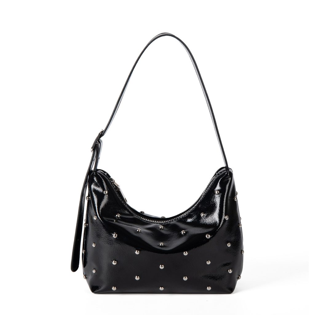 A glossy black vegan leather crescent bag covered in small silver studs, with an adjustable strap and top zipper.