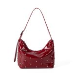 A glossy black vegan leather crescent bag covered in small silver studs, with an adjustable strap and top zipper. Additional product view 2.