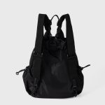 A black nylon drawstring backpack with ruffled cinch opening, side pockets, webbing straps, and a small top handle. Additional product view 6.