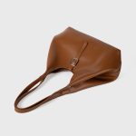 A slouchy black vegan leather tote with integrated shoulder straps and a thin vertical strap finished with a silver buckle. Additional product view 7.