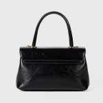 A dark brown glossy vegan leather top-handle flap bag with a gold-tone oval twist-lock centered on the front. Additional product view 8.