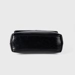 A dark brown glossy vegan leather top-handle flap bag with a gold-tone oval twist-lock centered on the front. Additional product view 9.