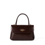 A dark brown glossy vegan leather top-handle flap bag with a gold-tone oval twist-lock centered on the front. Additional product view 6.