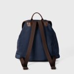 A black nylon backpack with cognac brown vegan leather piping, a top flap over a drawstring, and two lower front pockets. Additional product view 5.