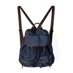 A black nylon backpack with cognac brown vegan leather piping, a top flap over a drawstring, and two lower front pockets. Additional product view 3.