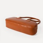 A long black vegan leather east-west baguette with two thin tubular straps and a silver zipper along the top. Additional product view 4.
