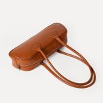 A long black vegan leather east-west baguette with two thin tubular straps and a silver zipper along the top. Additional product view 6.