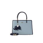A structured sky blue satchel with navy trim, gold-tone hardware, a single top handle, and a navy elephant charm. Additional product view 2.
