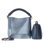 A blue geometric-patterned bucket bag with a twisted navy top handle, matching inner pouch, and detachable crossbody strap.