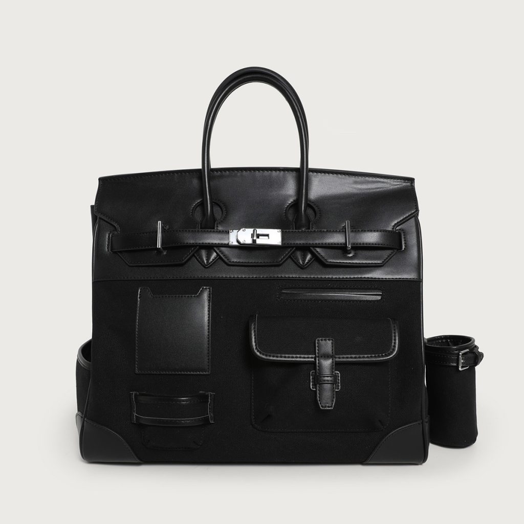 A large black utility tote with mixed canvas and vegan leather panels, multiple cargo pockets, and a silver turn-lock.