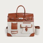 A large black utility tote with mixed canvas and vegan leather panels, multiple cargo pockets, and a silver turn-lock. Additional product view 4.