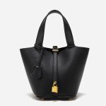 A taupe pebbled vegan leather bucket bag with dual top handles, a gold padlock on the center strap, and a matching clochette. Additional product view 2.