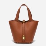 A taupe pebbled vegan leather bucket bag with dual top handles, a gold padlock on the center strap, and a matching clochette. Additional product view 4.