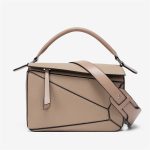A light beige pebbled vegan leather puzzle bag with diagonal panels, a rolled top handle, and an adjustable shoulder strap. Additional product view 2.