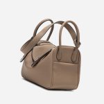 A taupe pebbled vegan leather Lindy bag with side-set handles, a shoulder strap, and silver circular turn-locks. Additional product view 6.