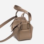 A taupe pebbled vegan leather Lindy bag with side-set handles, a shoulder strap, and silver circular turn-locks. Additional product view 7.